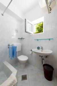 a white bathroom with a sink and a toilet at Apartments Melita in Crikvenica