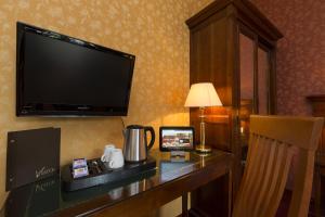 a hotel room with a desk with a television on a wall at Hotel Viator - Gare de Lyon in Paris