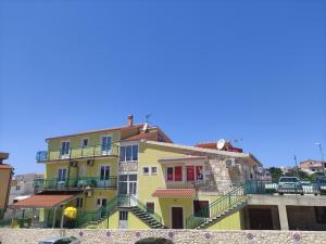 a yellow building with stairs on the side of it at Apartments Jadrijević Brne in Primošten