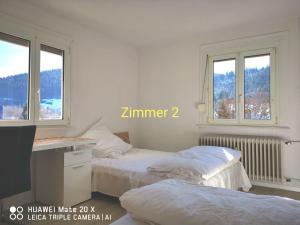 two beds in a white room with two windows at Rosen Garten Haus in Titisee-Neustadt