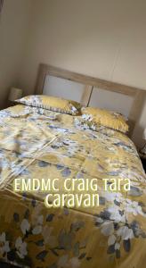 a bed with a floral comforter on top of it at EMDMC Craig Tara Caravan in Ayr