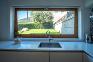 eine Küchenspüle mit einem Fenster über einer Küchentheke in der Unterkunft Villa Tavares Suítes in Arouca