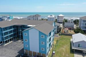 an aerial view of a blue apartment building and the ocean at Hang Ten Hideaway, pool, Condo, Parking, payment due upon booking Host will reach out once you book in Carolina Beach