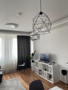 uma sala de estar com uma televisão num armário branco em BRL Apartman em Nyíregyháza