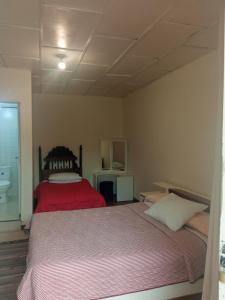 - une chambre avec un grand lit et une couverture rouge dans l'établissement HOTEL DUX, à Tunja