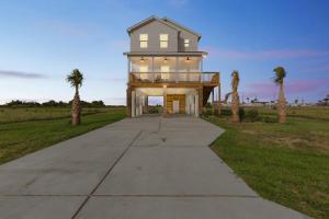 ein Haus auf einem Betonweg mit Palmen in der Unterkunft Cozy 3 Bedroom Family Beach Home in Galveston in Galveston