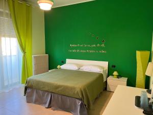 1 dormitorio con una pared verde y 1 cama en Color House Malpensa B&B, en Cassano Magnago