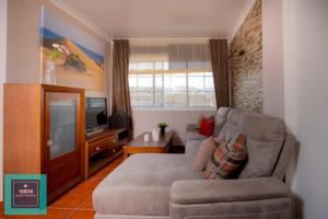 a living room with a couch and a television at Tita Apartment Montaña La Data in San Bartolomé