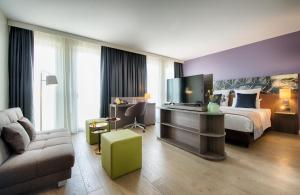 a hotel room with a bed and a television at Leonardo Hotel Munich City East in Munich