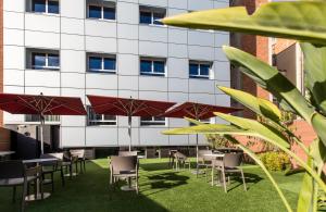 uma fila de mesas e cadeiras com guarda-sóis em frente a um edifício em Leonardo Boutique Hotel Barcelona Sagrada Familia em Barcelona