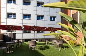 eine Reihe von Tischen und Stühlen mit Sonnenschirmen vor einem Gebäude in der Unterkunft Leonardo Boutique Hotel Barcelona Sagrada Familia in Barcelona