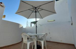 a table and chairs with an umbrella in a room at Visconde de Estoi in Faro