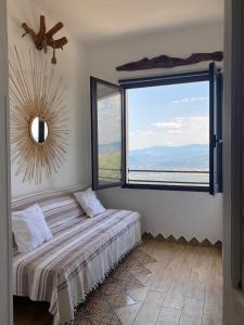ein Schlafzimmer mit einem Bett und einem großen Fenster in der Unterkunft Steddueoro in Baunei