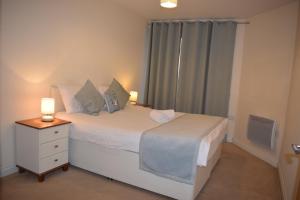 een slaapkamer met een bed met een nachtkastje en een raam bij 2 bedroom & 2 bathroom apartment - TcA58 in Watford