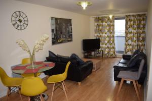 een woonkamer met een tafel en gele stoelen bij 2 bedroom & 2 bathroom apartment - TcA58 in Watford