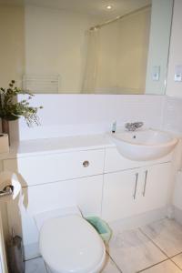 Baño blanco con aseo y lavamanos en 2 bedroom & 2 bathroom apartment - TcA58 en Watford