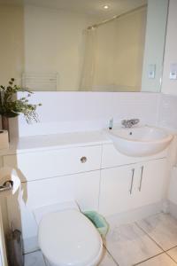een witte badkamer met een toilet en een wastafel bij 2 bedroom & 2 bathroom apartment - TcA58 in Watford