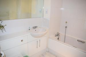 een witte badkamer met een wastafel en een bad bij 2 bedroom & 2 bathroom apartment - TcA58 in Watford