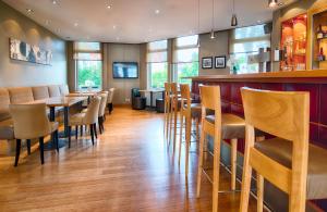 a restaurant with wooden tables and chairs at Leonardo Hotel Hamburg Airport in Hamburg