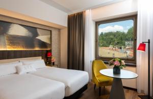 um quarto de hotel com uma cama, uma mesa e uma janela em NYX Hotel Bilbao by Leonardo Hotels em Bilbau