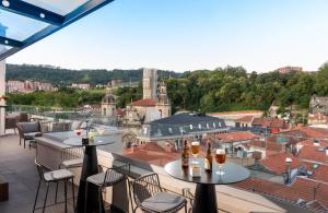 uma varanda com mesas e cadeiras e vista para a cidade em NYX Hotel Bilbao by Leonardo Hotels em Bilbau