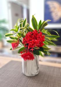 um vaso branco cheio de flores vermelhas numa mesa em Hitivai apartment em Papeete