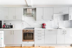 uma cozinha branca com armários brancos e um aparelho vermelho em Dunstan House Luxury Holiday Home with free parking em Oxford