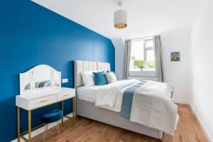 Dunstan House Luxury Holiday Home with free parking في أوكسفورد: غرفة نوم زرقاء وبيضاء مع سرير ومرآة