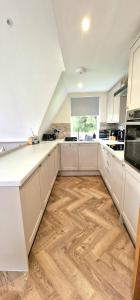 a kitchen with white cabinets and a wooden floor at Bonnie Lodge-Lochside Location with Hot Tub in Invergarry