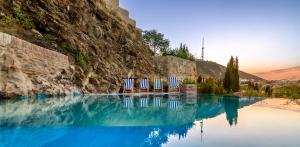 two chairs and a pool of water with a mountain at Castle in Old Town in Tbilisi City