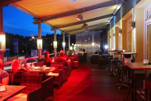 Hotel Stadt Daun في داون: مطعم والكراسي الحمراء والناس جالسين على الطاولات