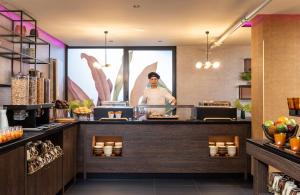 a chef standing behind the counter of a restaurant at NYX Hotel Madrid by Leonardo Hotels in Madrid