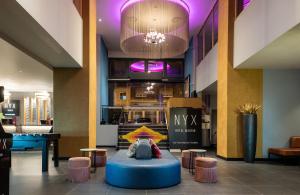 a lobby with a blue table and stools and a chandelier at NYX Hotel Madrid by Leonardo Hotels in Madrid
