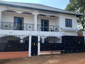una casa blanca con una puerta de hierro negro en Villa luxueuse - Odza - Yaoundé en Yaundé