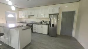 a kitchen with white cabinets and a stainless steel refrigerator at Tranquility Suites- Feels like Home in Choiseul
