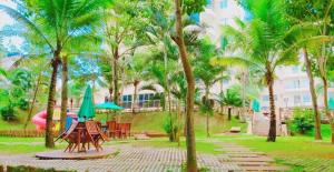 um parque com mesas e guarda-sóis e palmeiras em Thermas Paradise Apart em Rio Quente
