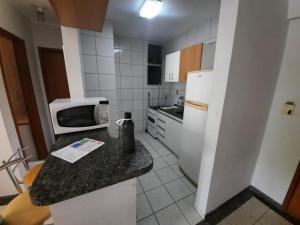 a small kitchen with a microwave and a refrigerator at Thermas Paradise Apart in Rio Quente