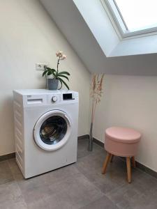 eine Waschmaschine in einem Zimmer mit einem rosa Hocker in der Unterkunft Studio - Apartment Steinmetz mit Balkon in Reken