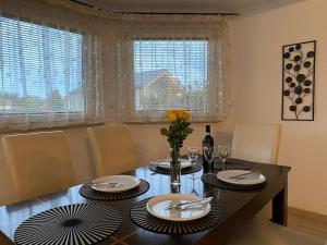 a dining room table with plates and a vase of flowers at 4 Bedroom family house with access to a hot tub in Goczałkowice-Zdrój