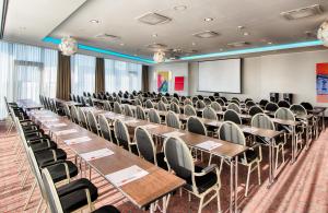 a conference room with tables and chairs and a screen at Leonardo Hotel Munich City South in Munich