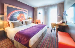 ein Hotelzimmer mit einem großen Bett und einem Schreibtisch in der Unterkunft Leonardo Hotel Munich City South in München