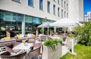 eine Außenterrasse mit Tischen und Stühlen sowie ein Gebäude in der Unterkunft Leonardo Hotel Munich City South in München