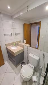 a bathroom with a toilet and a sink and a mirror at Condomínio Barretos Thermas Park - Flat Parque do Peão in Barretos