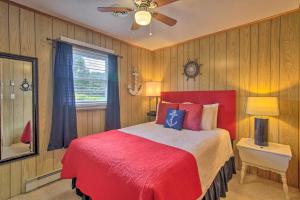 een slaapkamer met een rood bed en een plafondventilator bij Lakefront Hiwassee Home with Private Dock and Deck! in Hiwassee