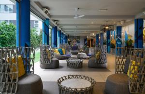NYX Hotel Milan by Leonardo Hotels في ميلانو: لوبي فيه كنب وكراسي وجدران زرقاء