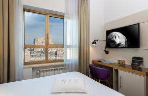 Cette chambre comprend un lit, un bureau et une fenêtre. dans l'établissement NYX Hotel Milan by Leonardo Hotels, à Milan