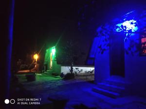 a house at night with a green and blue light at Chalé Roots in São Thomé das Letras