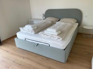 uma cama com lençóis brancos e toalhas em Int. Appartment Kolbermoor em Kolbermoor