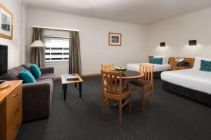 a hotel room with a bed and a couch and a table at Rydges Darwin Central in Darwin