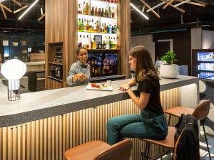 dos mujeres sentadas en un mostrador con un plato de comida en ibis Strasbourg Centre Les Halles, en Estrasburgo